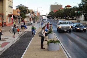 pedestrians and bikers at crosswalk of busy street