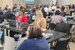 Employees on laptops in a conference room.